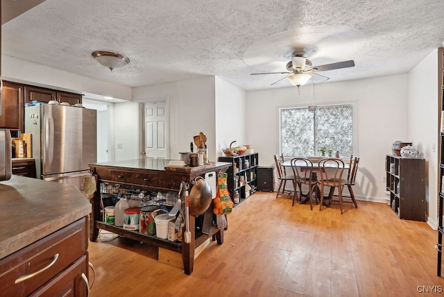 kitchen with light hardwood / wood-style floors, stainless steel refrigerator, a textured ceiling, and ceiling fan