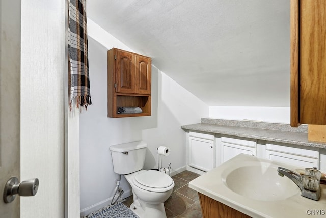 bathroom with vanity, vaulted ceiling, toilet, and tile patterned flooring