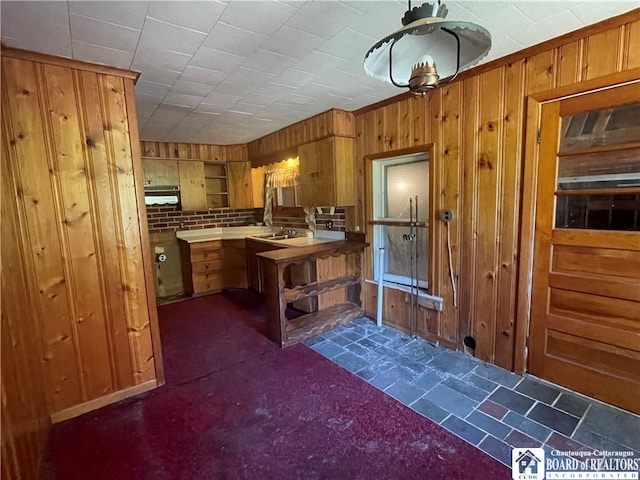 kitchen with wood walls and dark colored carpet