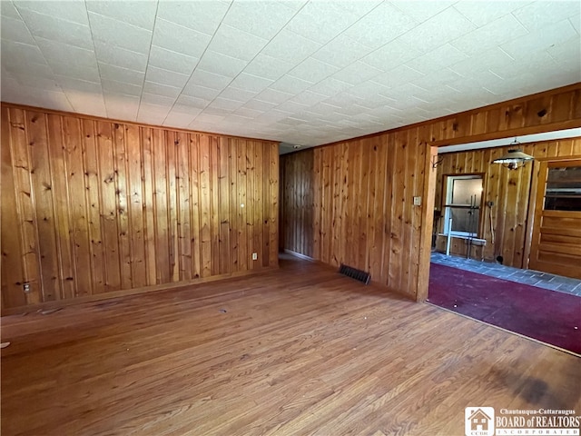 empty room featuring hardwood / wood-style flooring and wood walls