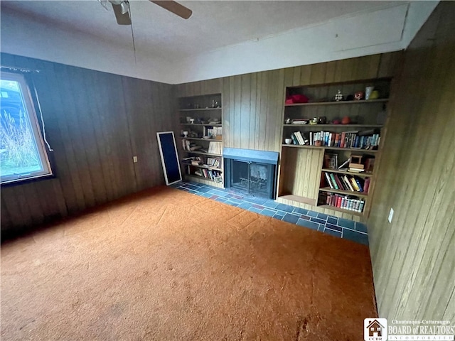 interior space featuring ceiling fan, carpet flooring, and built in shelves