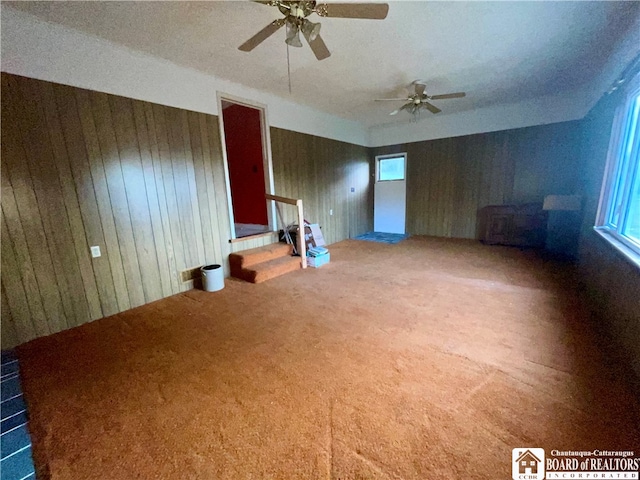 unfurnished room featuring wooden walls, carpet flooring, and ceiling fan