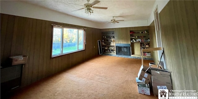 interior space with wooden walls, a textured ceiling, and ceiling fan