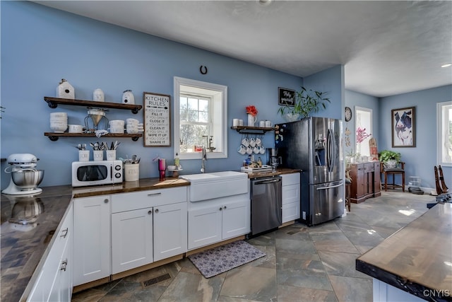 kitchen with wooden counters, sink, white cabinets, and stainless steel appliances