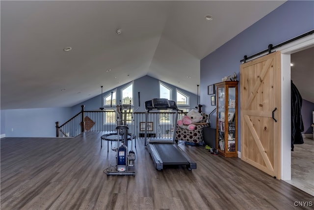 exercise area with hardwood / wood-style flooring, vaulted ceiling, and a barn door