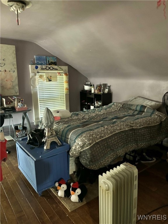 bedroom with lofted ceiling, radiator heating unit, and dark hardwood / wood-style flooring