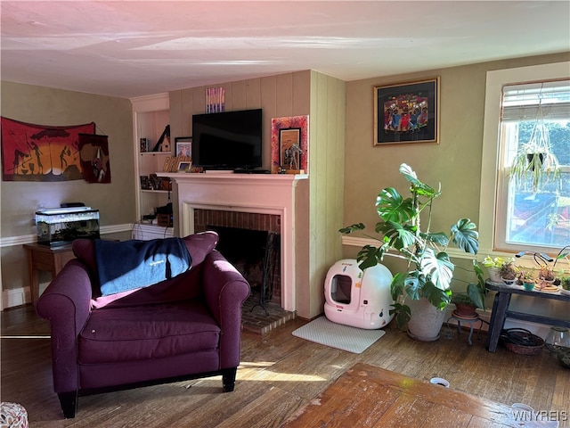 living room featuring wood-type flooring and a brick fireplace