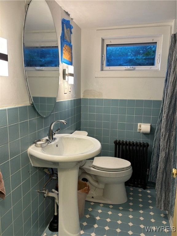 bathroom featuring tile walls, toilet, and radiator