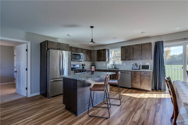 kitchen featuring a center island, stainless steel appliances, hanging light fixtures, and plenty of natural light