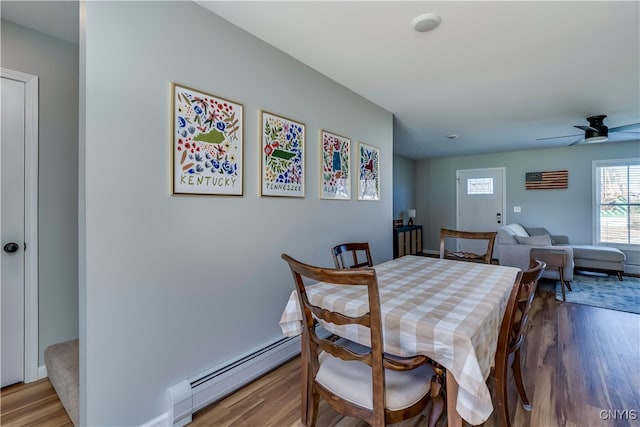 dining area with a baseboard radiator, wood-type flooring, and ceiling fan