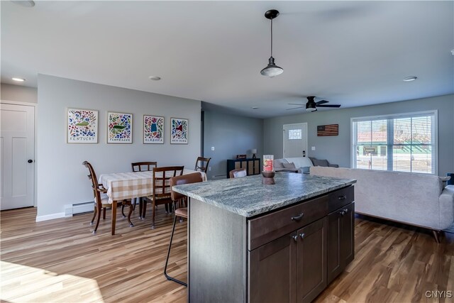 kitchen featuring dark brown cabinetry, decorative light fixtures, wood-type flooring, and ceiling fan