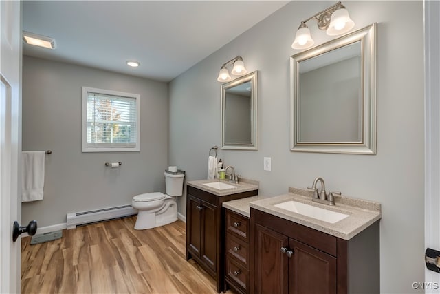 bathroom featuring toilet, a baseboard heating unit, hardwood / wood-style flooring, and vanity