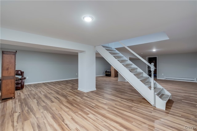 basement with light hardwood / wood-style flooring and a baseboard radiator