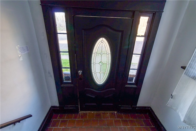 foyer featuring plenty of natural light and dark tile patterned floors