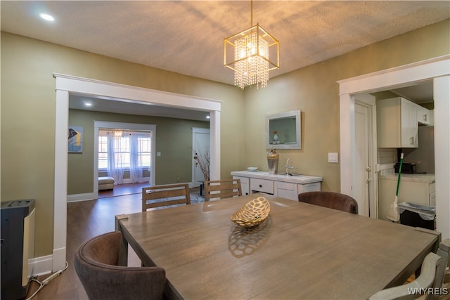 dining area featuring a notable chandelier, a textured ceiling, and dark hardwood / wood-style flooring