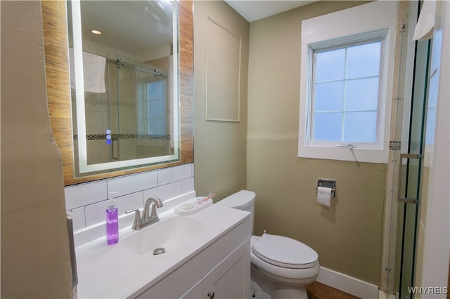 bathroom with vanity, tasteful backsplash, toilet, and walk in shower