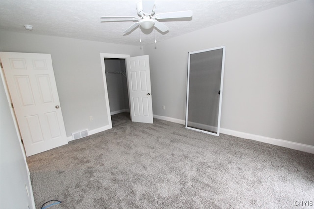 unfurnished bedroom with a spacious closet, ceiling fan, light carpet, and a textured ceiling