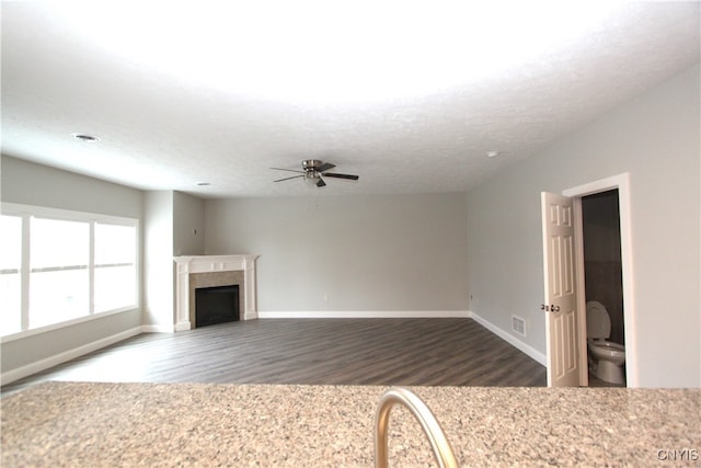 unfurnished living room featuring a textured ceiling, dark hardwood / wood-style floors, and ceiling fan