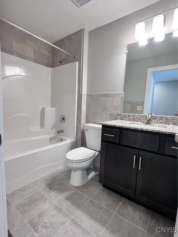 full bathroom featuring tiled shower / bath, vanity, a textured ceiling, and toilet