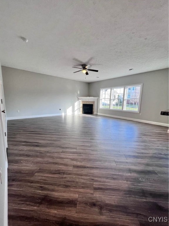 unfurnished living room with ceiling fan, a textured ceiling, and dark hardwood / wood-style floors