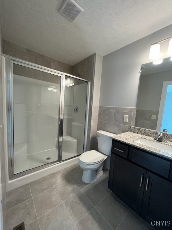 bathroom with a shower with door, tile patterned floors, toilet, vanity, and a textured ceiling