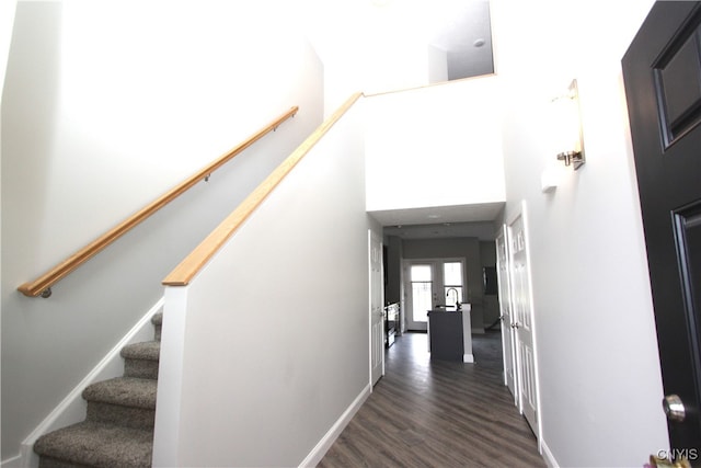 stairway with hardwood / wood-style floors and a towering ceiling