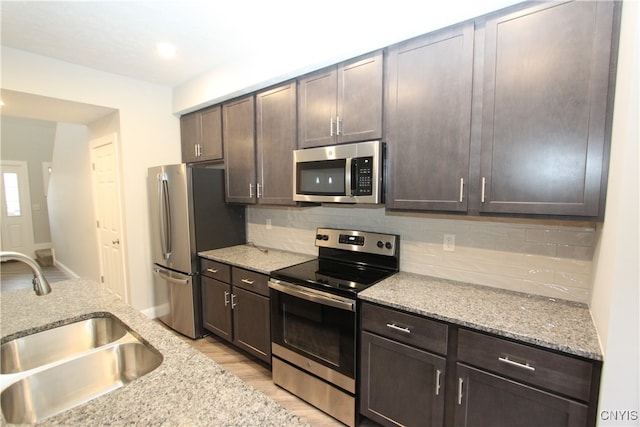 kitchen featuring light hardwood / wood-style flooring, dark brown cabinets, stainless steel appliances, sink, and tasteful backsplash