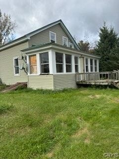 back of property with a wooden deck and a yard