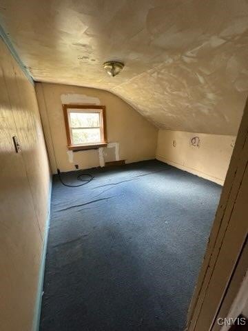 bonus room featuring dark carpet and vaulted ceiling