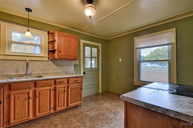 kitchen with crown molding, a healthy amount of sunlight, sink, and hanging light fixtures