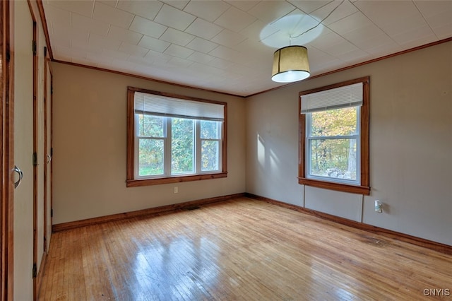 spare room featuring crown molding and light wood-type flooring