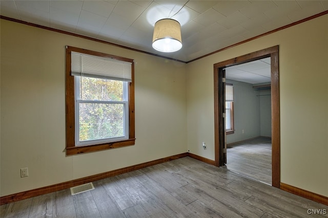 spare room with ornamental molding and light wood-type flooring