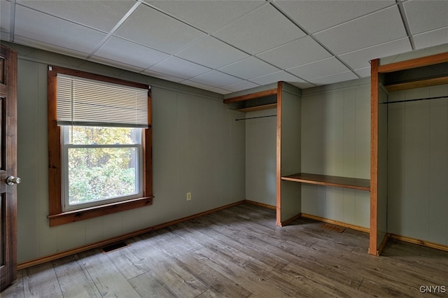 unfurnished bedroom featuring a closet, a drop ceiling, and light hardwood / wood-style floors