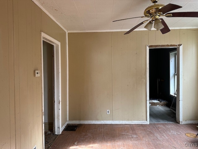 unfurnished room with hardwood / wood-style flooring, wood walls, and ceiling fan