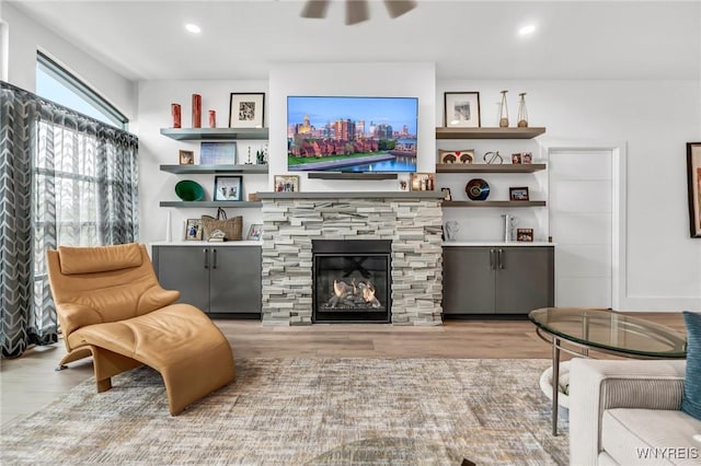 sitting room with a stone fireplace and light hardwood / wood-style floors