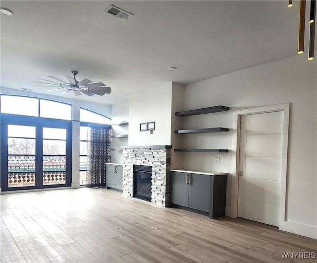 unfurnished living room featuring ceiling fan, a fireplace, and light wood-type flooring