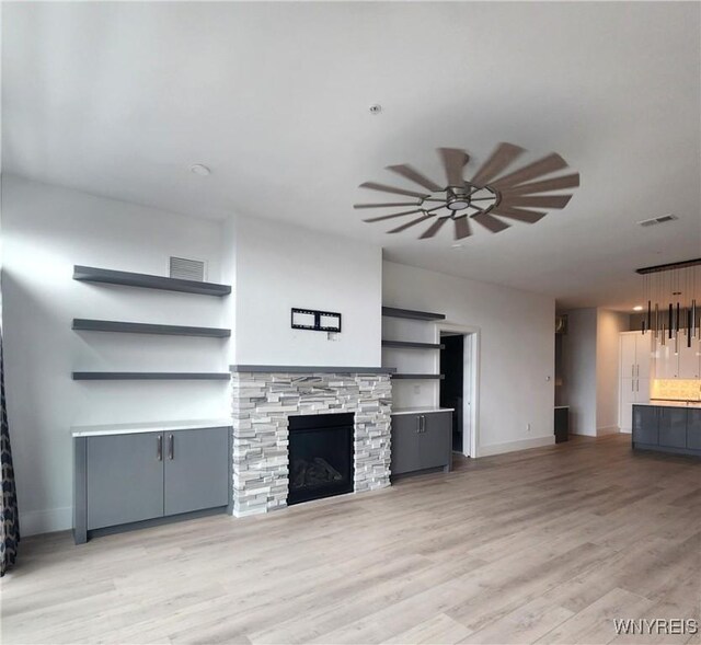 unfurnished living room featuring light hardwood / wood-style flooring, a fireplace, and ceiling fan