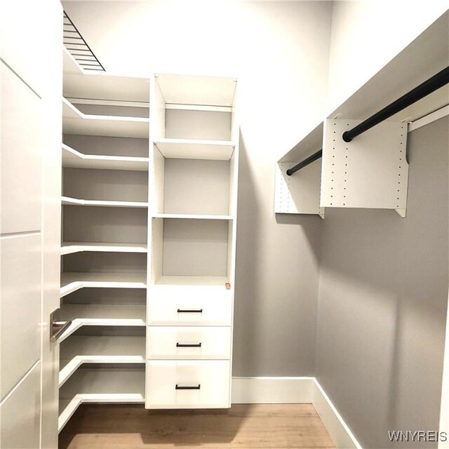 walk in closet with hardwood / wood-style flooring