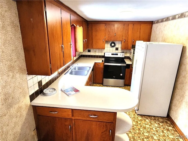 kitchen with sink, tasteful backsplash, white refrigerator, kitchen peninsula, and stainless steel electric stove