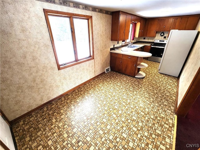 kitchen with decorative backsplash, sink, white fridge, and stainless steel range oven