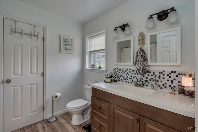 bathroom with backsplash, vanity, wood-type flooring, and toilet