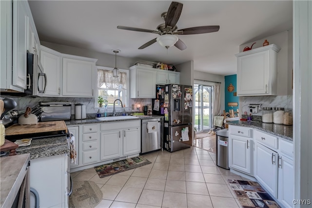 kitchen featuring stainless steel appliances, hanging light fixtures, a wealth of natural light, and white cabinets