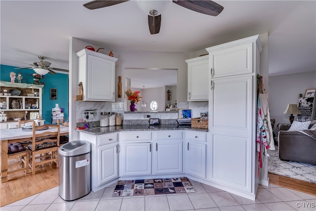 kitchen with white cabinets, tasteful backsplash, light wood-type flooring, and dark stone counters