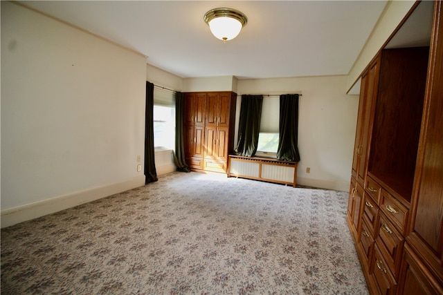 unfurnished bedroom featuring light carpet and radiator heating unit