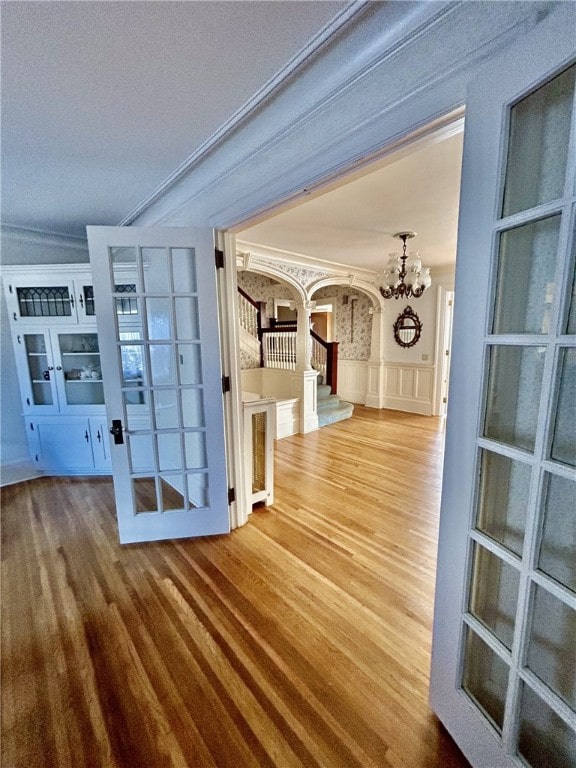 hallway with crown molding, a textured ceiling, hardwood / wood-style flooring, and a chandelier