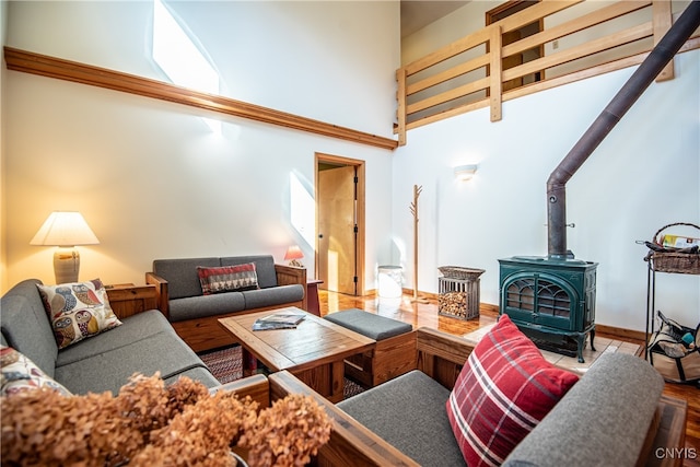 living room with a wood stove, hardwood / wood-style flooring, and a high ceiling