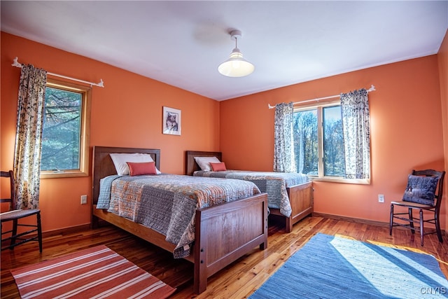 bedroom with multiple windows and hardwood / wood-style floors