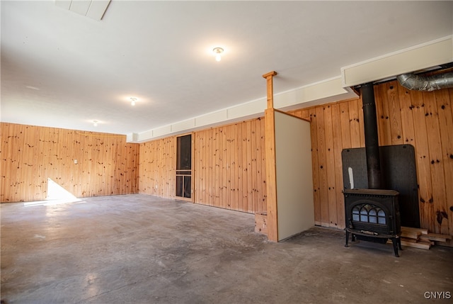 basement featuring a wood stove and wooden walls