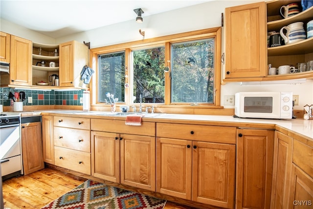 kitchen with backsplash, light hardwood / wood-style flooring, range hood, sink, and white appliances