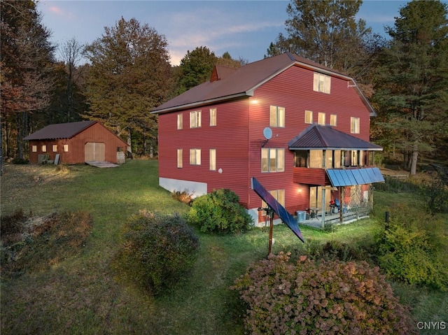 back house at dusk with a lawn and a storage shed